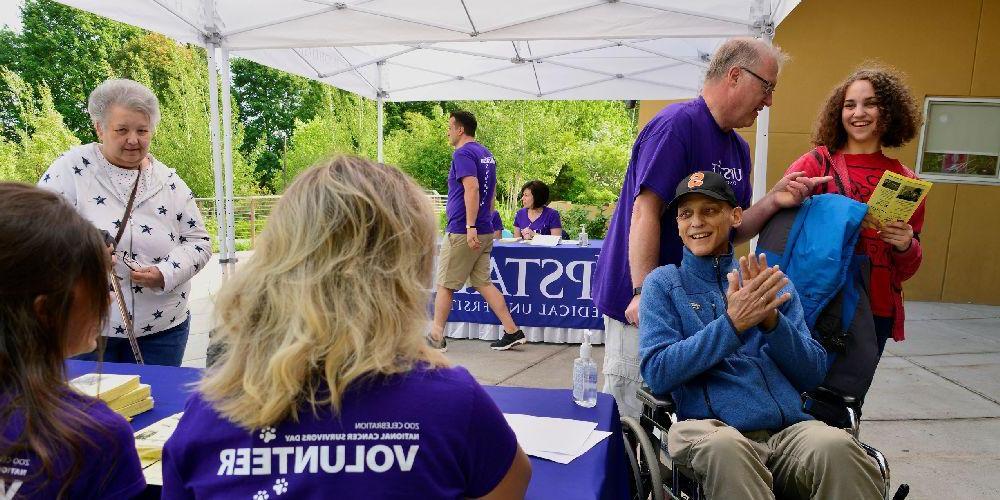 Volunteers are assisting a cancer patient at a registration table at the National Cancer Survivors Day celebration at the Rosamond Gifford Zoo.