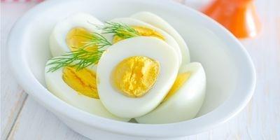 Hard boiled eggs sliced in half in a white bowl garnished with fresh dill.